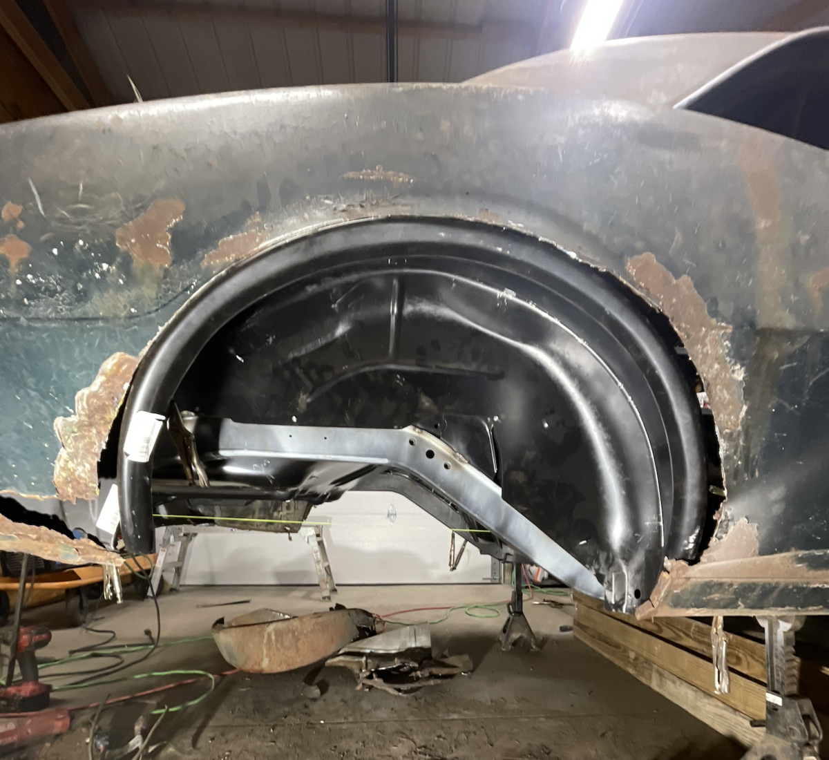 Welded steel frame repair and fabrication work on the rear wheel well of a classic car during automotive restoration.