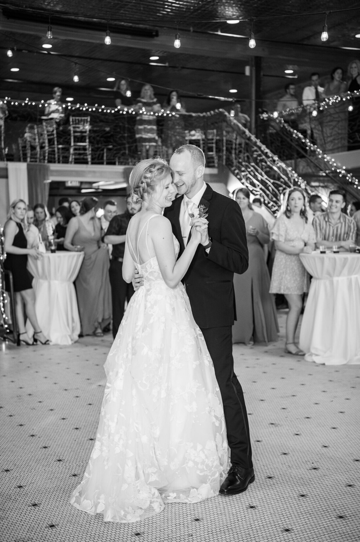bride and groom share first dance with guests watching in the background