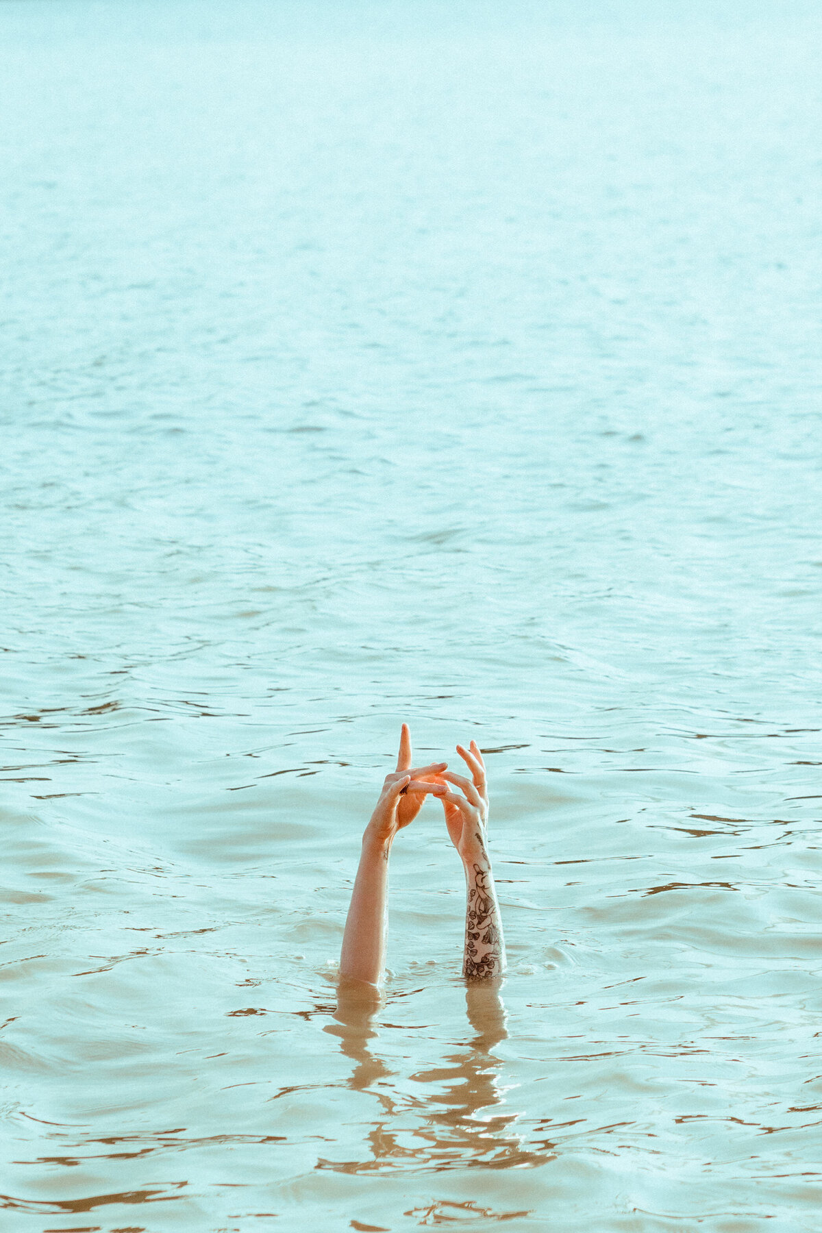 Arms raised above water in artistic lake portrait – symbolic creative expression captured by Mewphotovideo