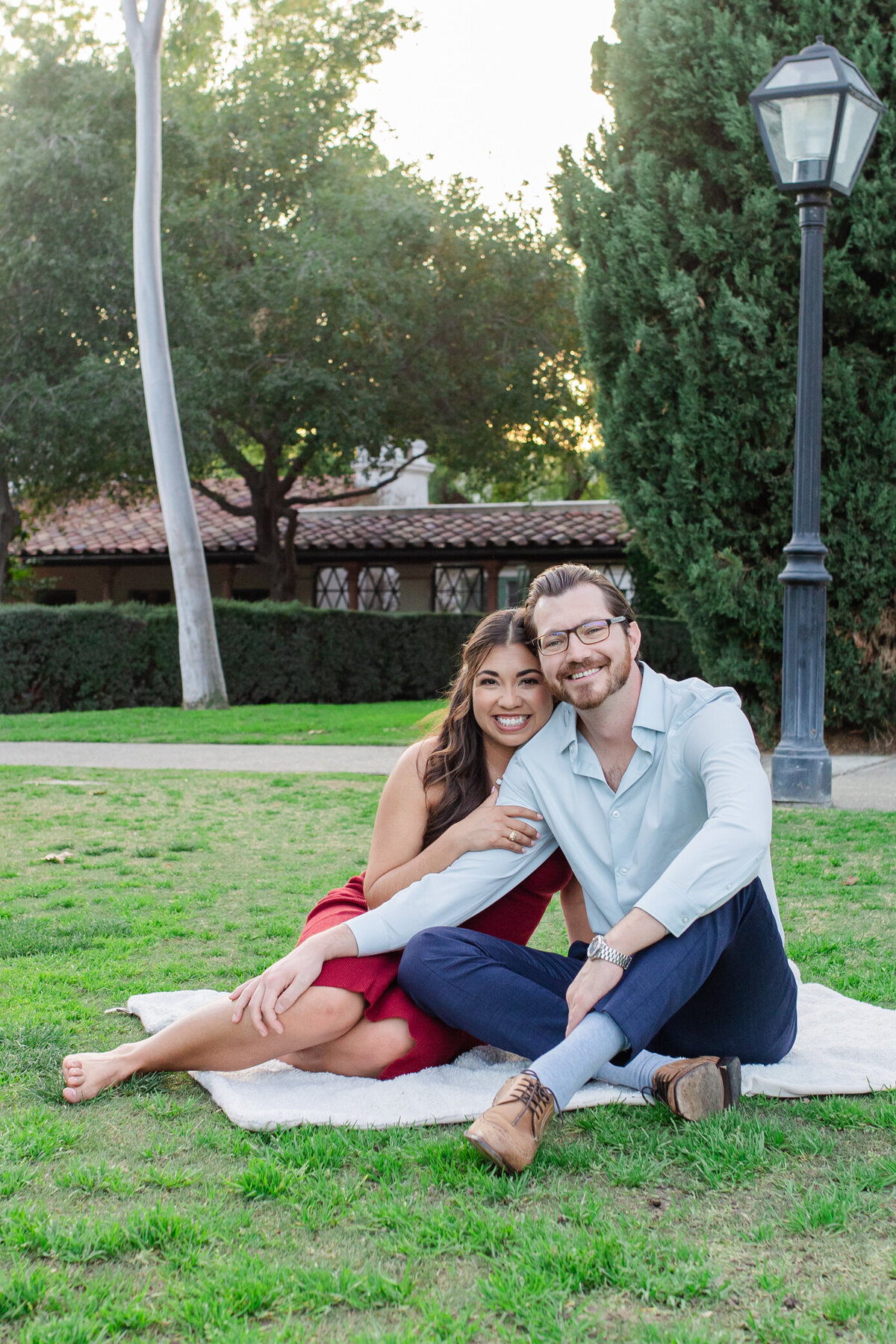 bride and groom-to-be cuddle on blanket