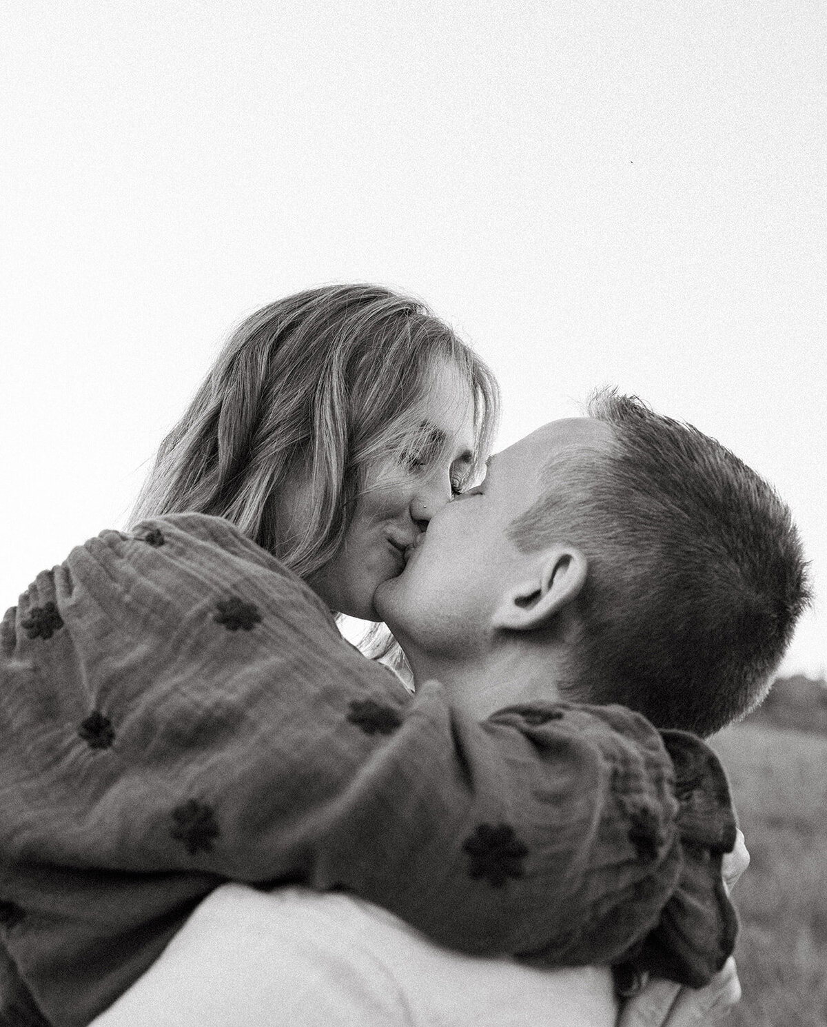 Mom and dad kissing while children play nearby during a candid lifestyle family photo session