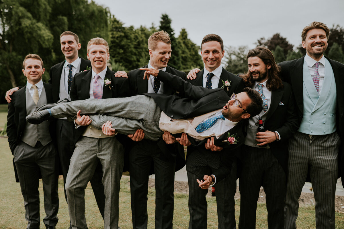 Groomsmen holding up groom