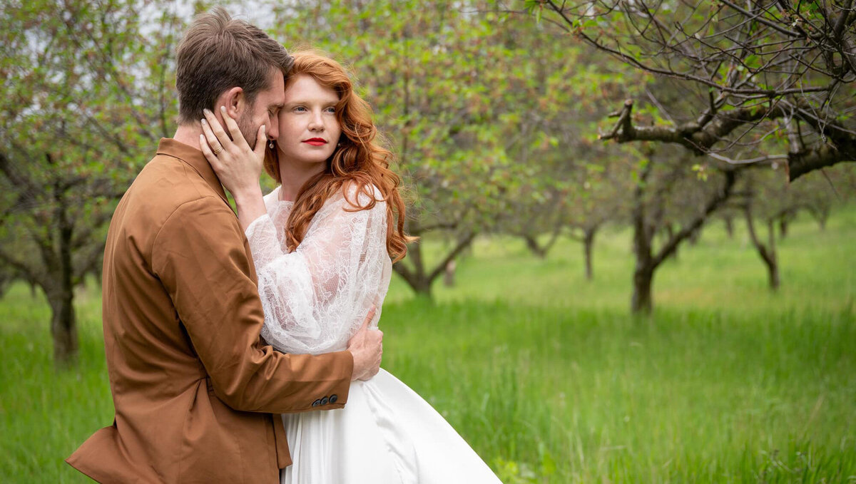 bride and groom in a grove of trees while bride with bright lipstick looks away