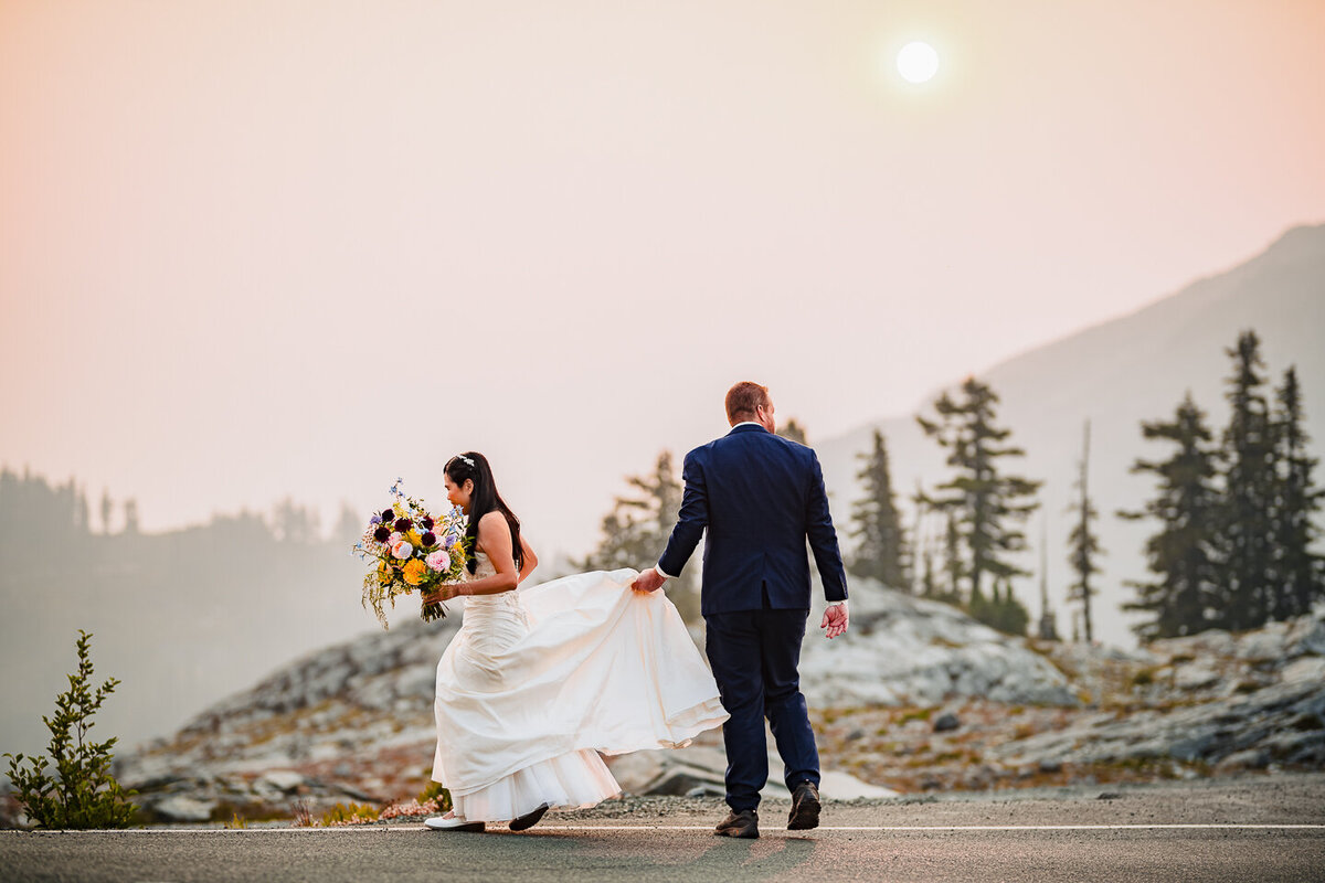 groom-holding-brides-dress-while-they-run-off-the-highway
