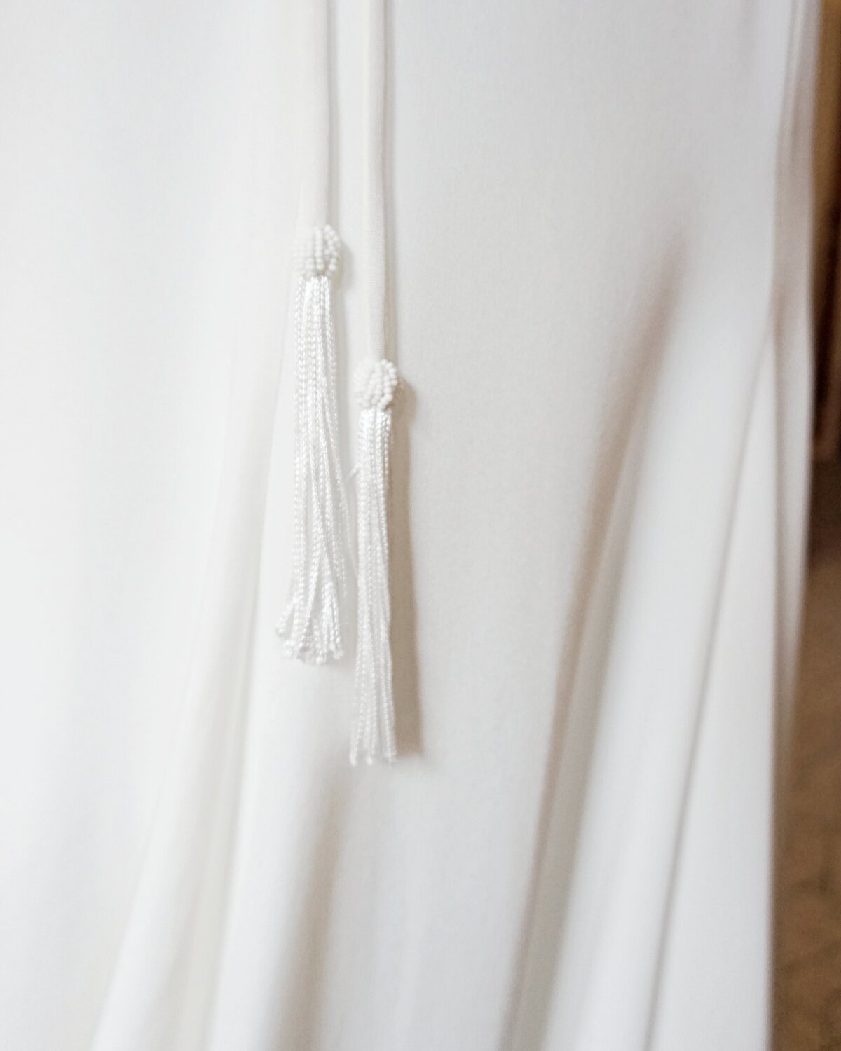 Close-up of the beaded tassels that adorn the ends of the waist ties on the Anila crepe wedding gown.