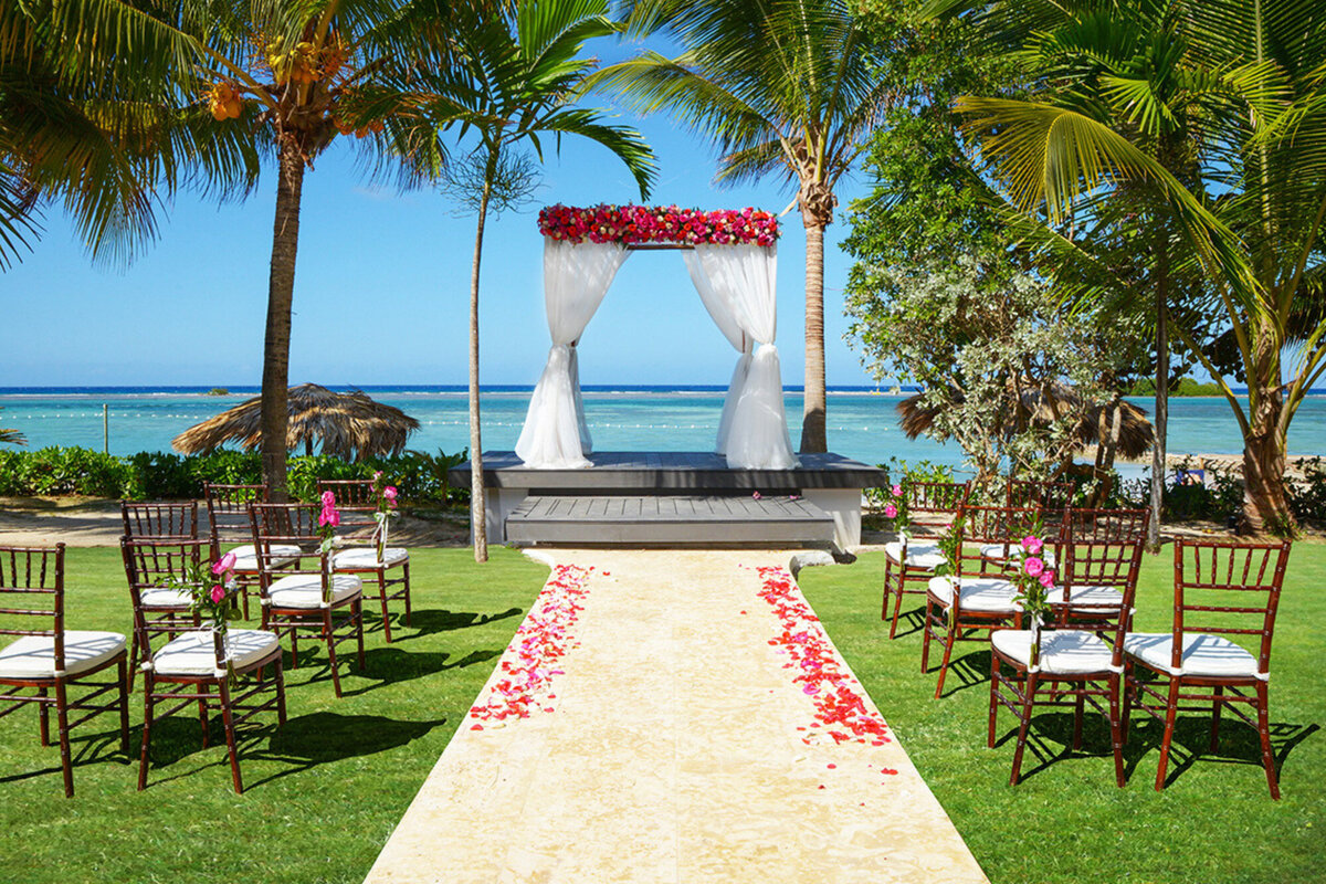 Elegant outdoor wedding ceremony site with pink floral details and a beach view