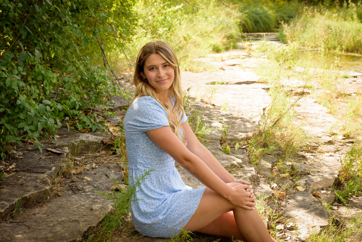 De Pere High School senior wearing light blue summer dress standing in creek at Fonferek Glen County Park in Green Bay, Wisconsin.