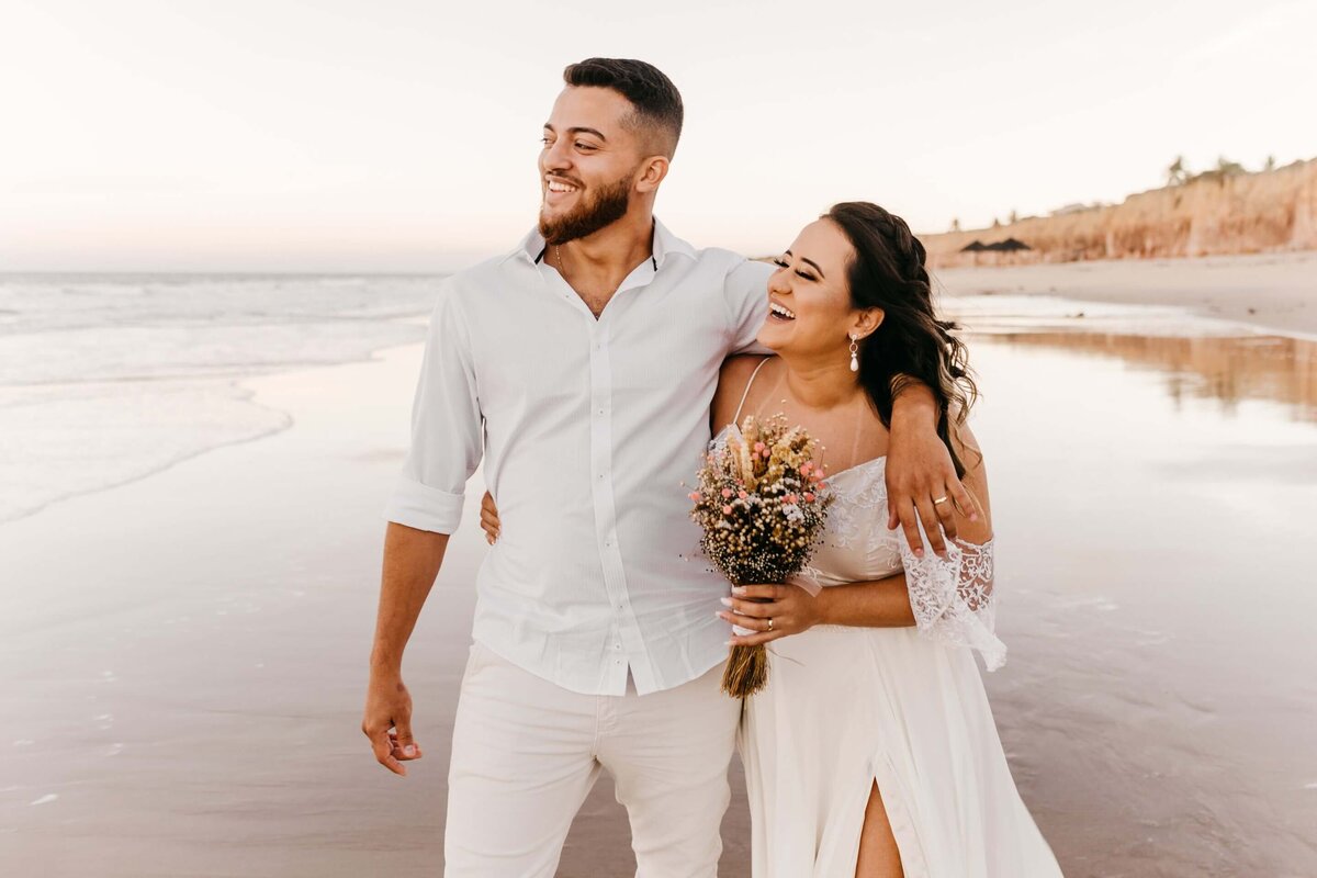 Delighted newlywed couple walking on beach