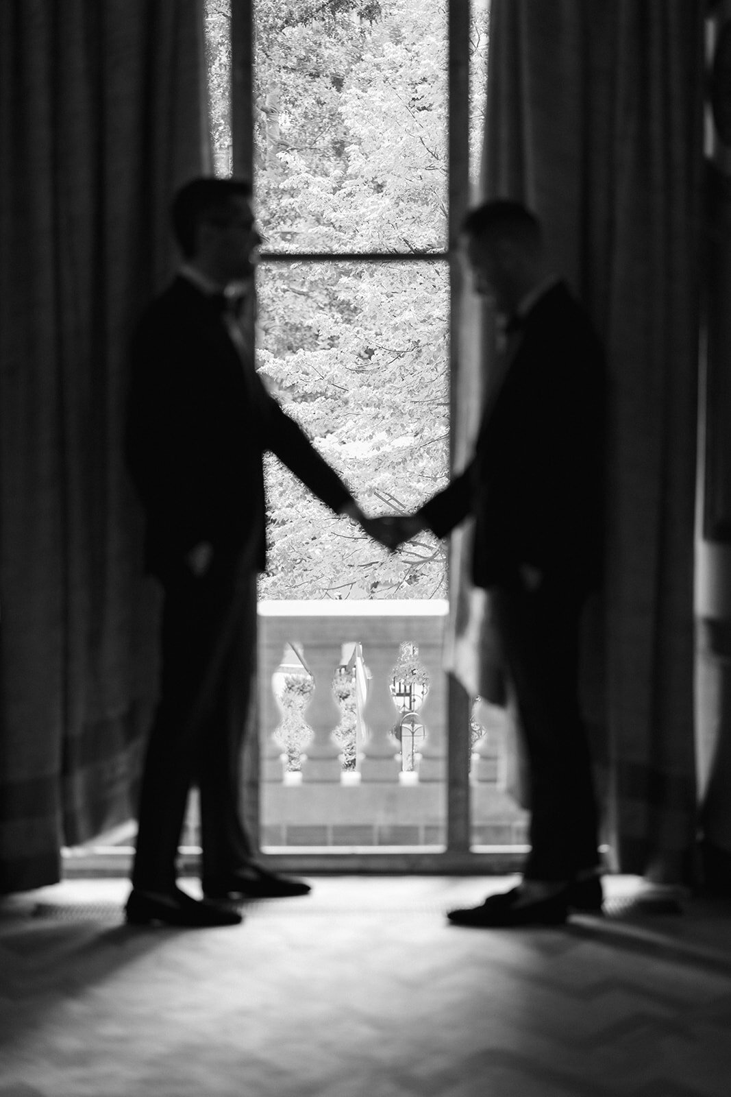 Two grooms holding hands, out of focus