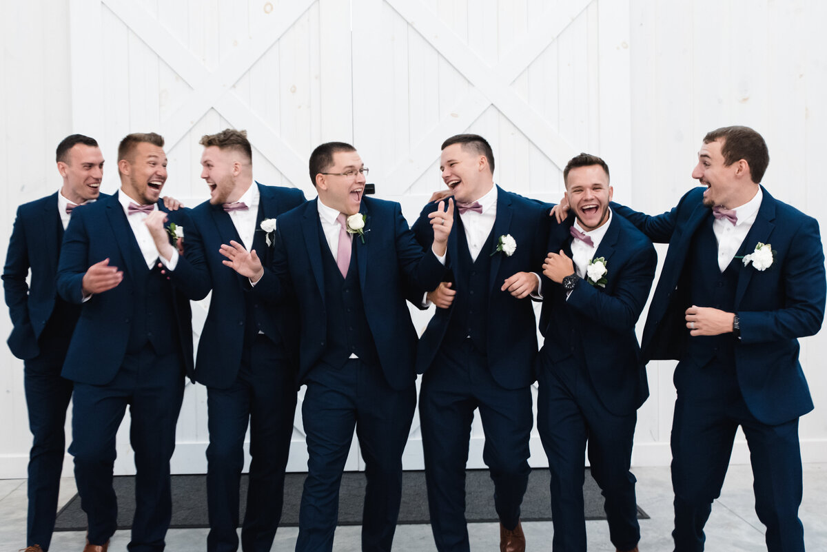 groom and groomsmen laugh and walk in barn at grayson house