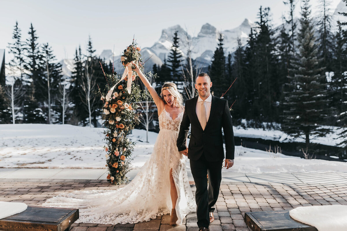 Bride and groom exit winter wedding ceremony at The Malcolm Hotel, a modern romantic wedding venue in Canmore, featured on the Brontë Bride Vendor Guide.