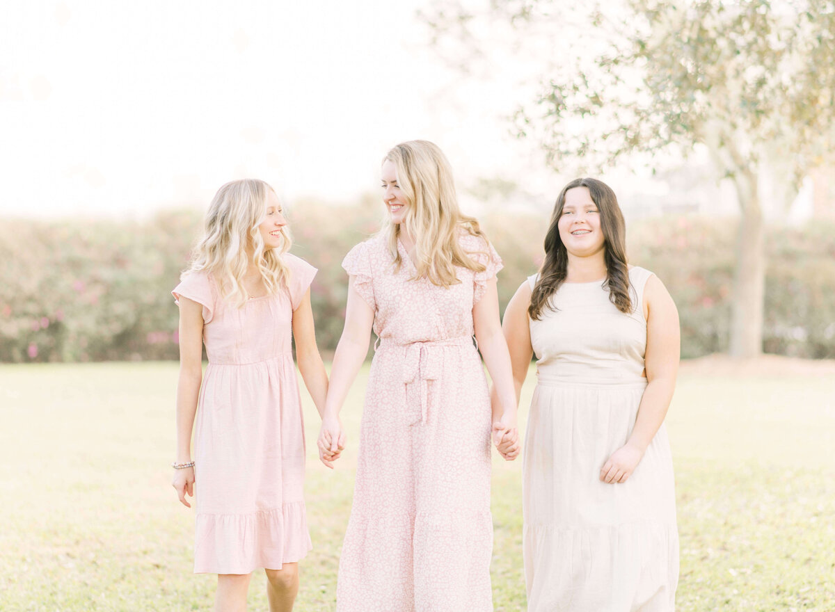 A blonde mother holds the hand of her two daughters during a family session in Hammond, LA. Photo taken by family and portrait photographer, Morgan Sandifer with Morgan Leigh Photography.