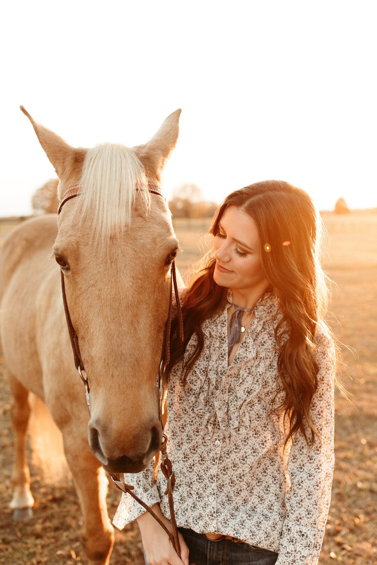High school senior girl with her horse on her farm  at golden hour