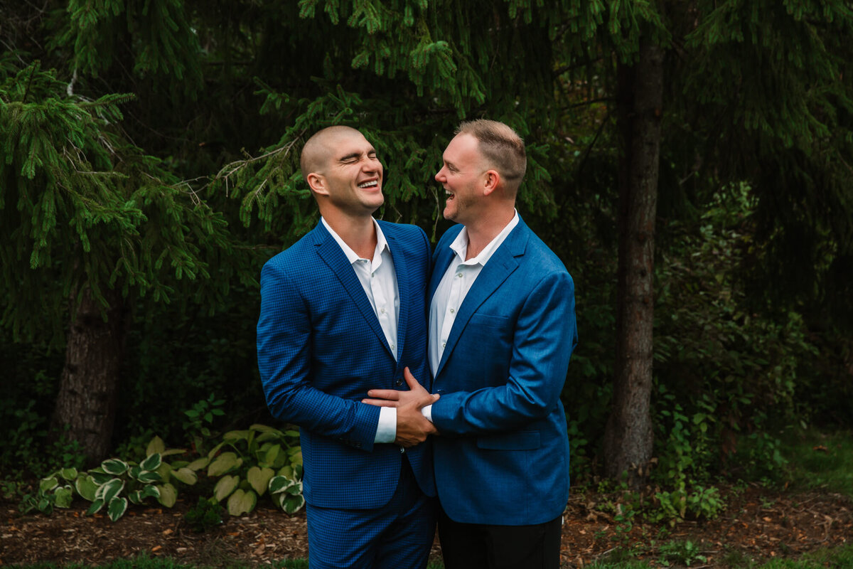 groom and groom smile and laugh while holding each other
