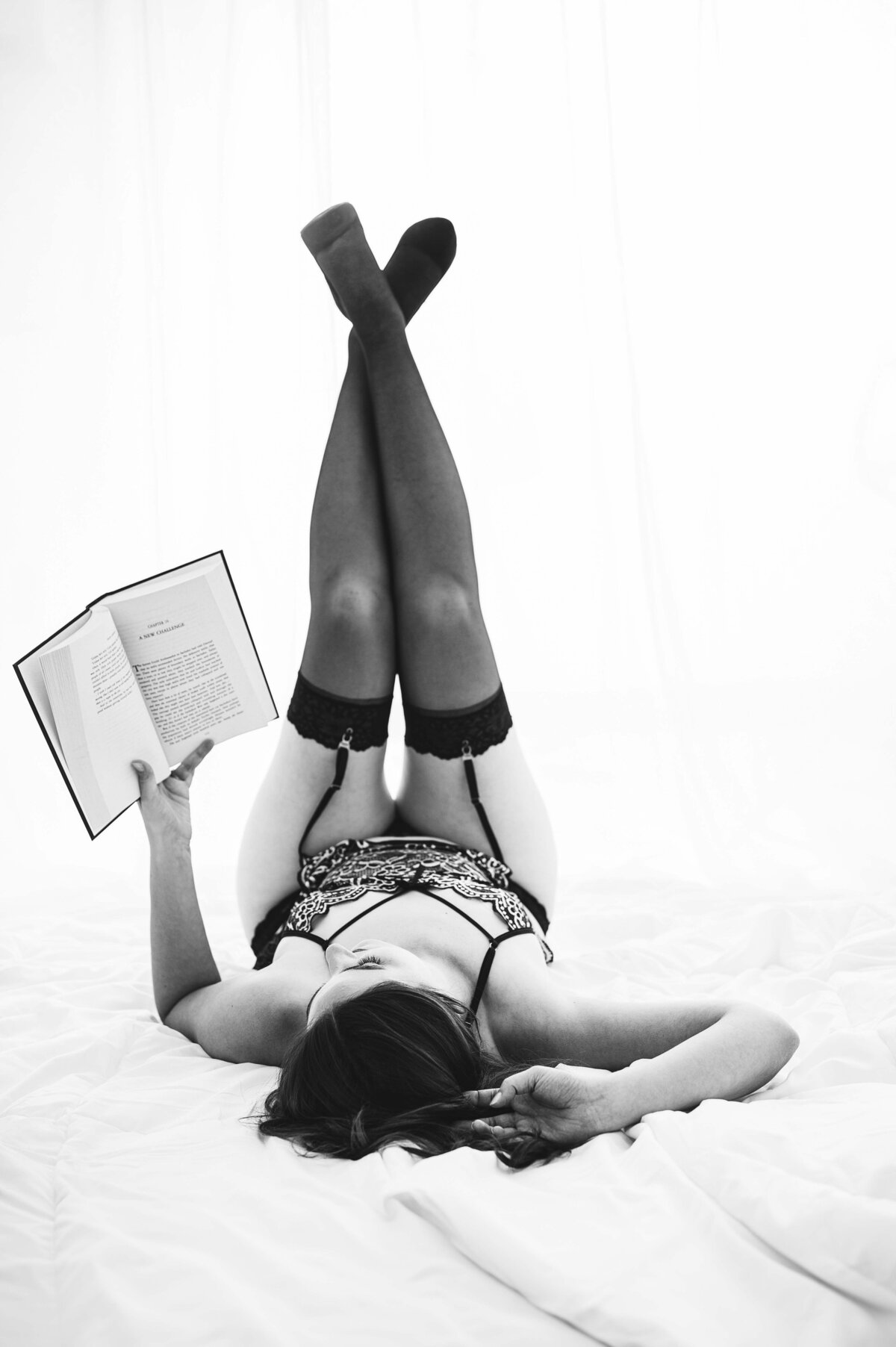 Woman in lingerie reading a book on bed captured by Leslie Q Photography