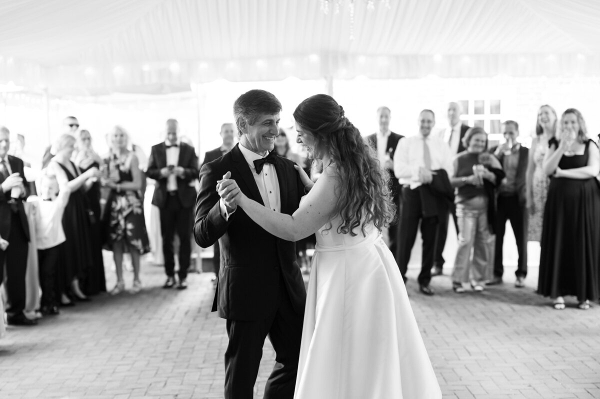 A newlywed couple during their first dance with wedding guests watching