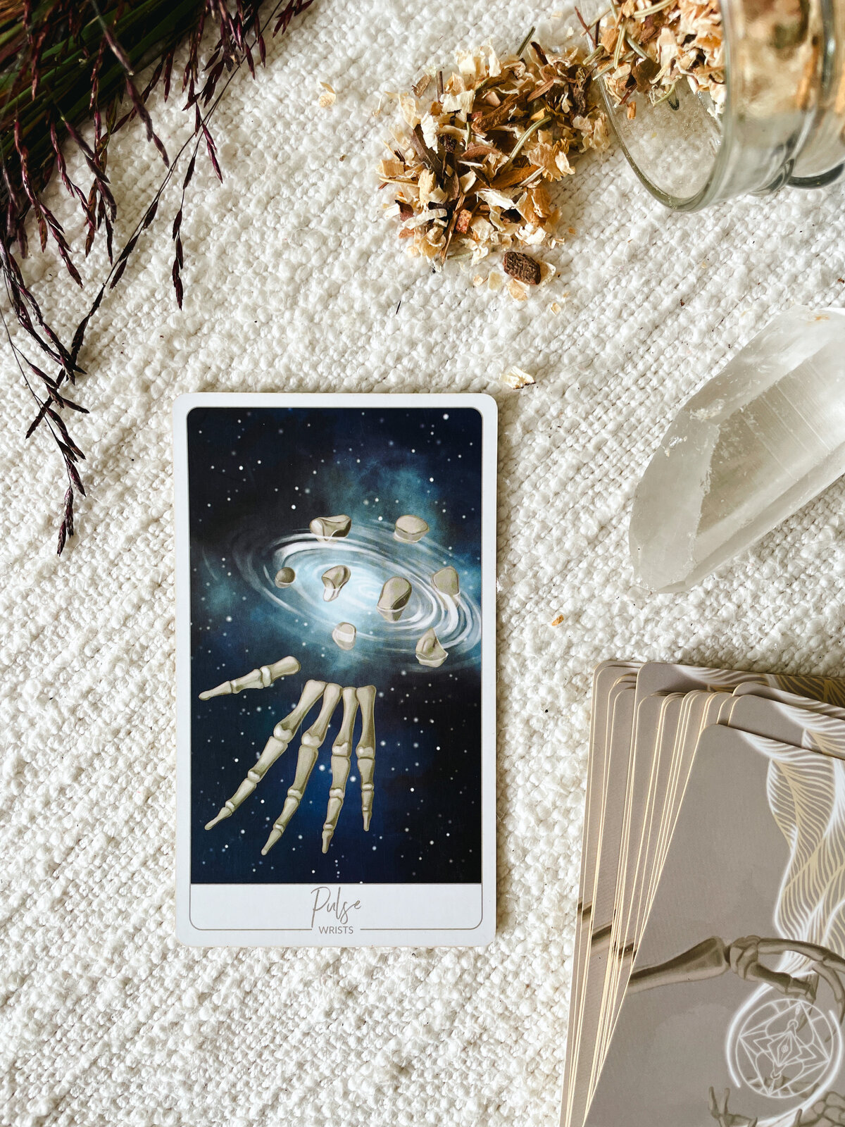 Close up of the "Pulse" Oracle Card which shows the bones of the wrist exploded apart and ripples radiating outward