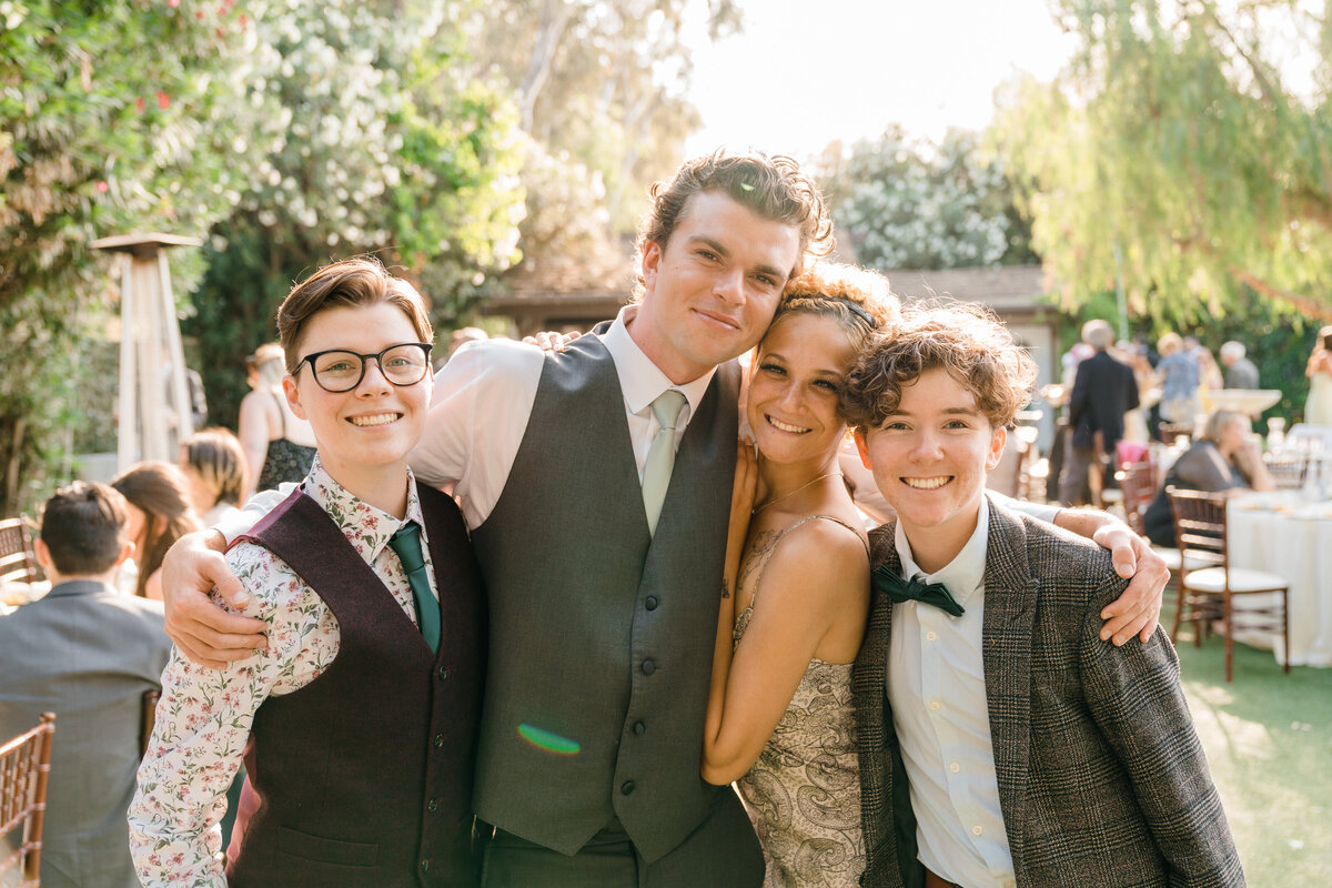four wedding guests smiling while side hugging each other