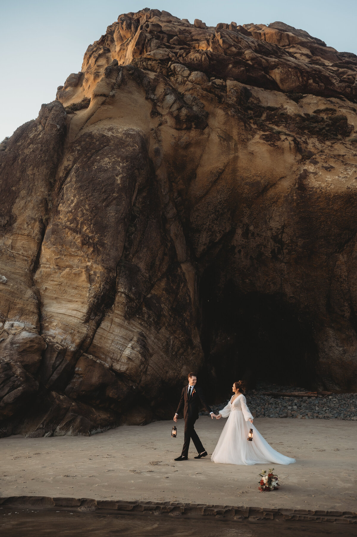 Photo of bride and groom walking on beach