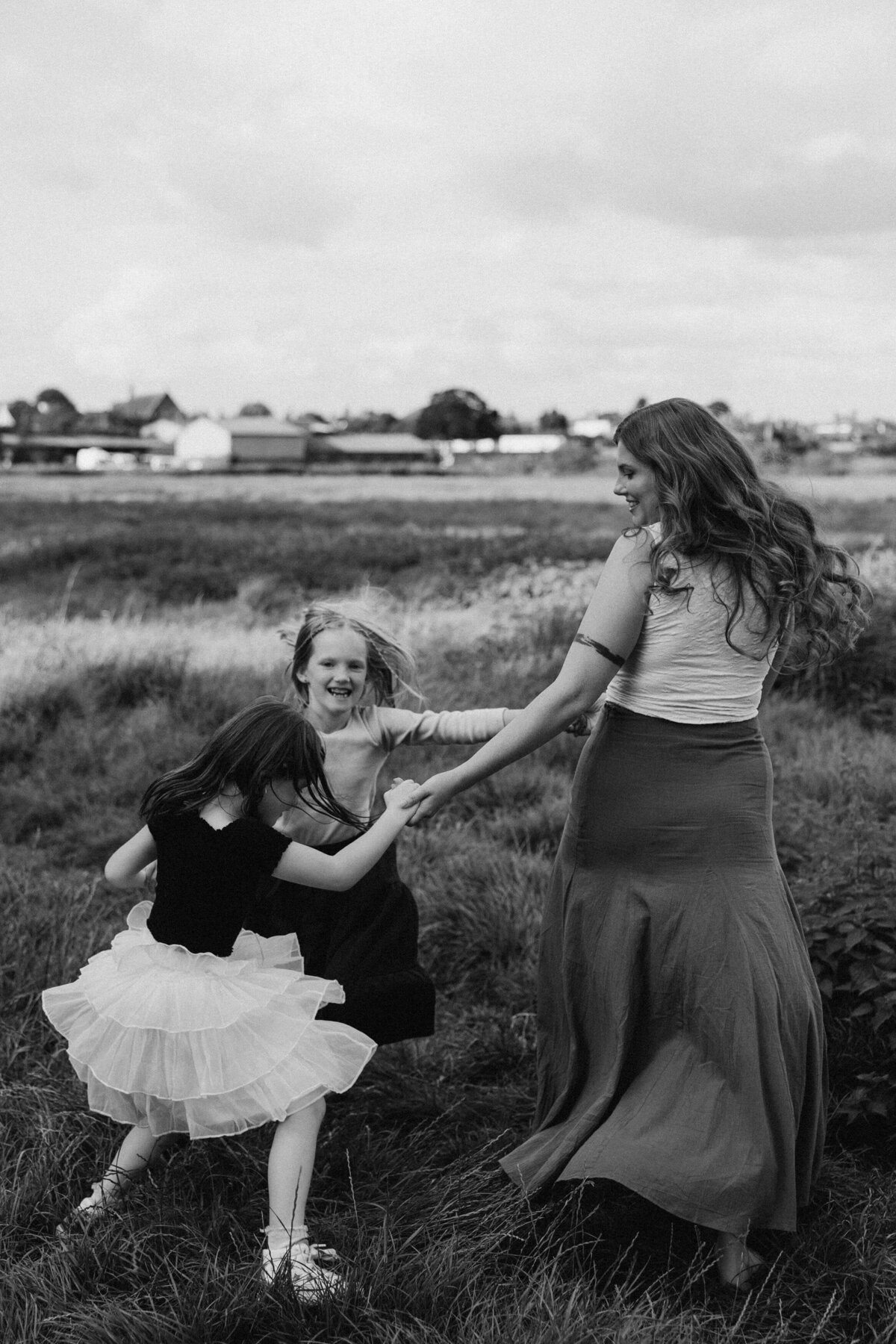 mother and her two daughters dancing in a field