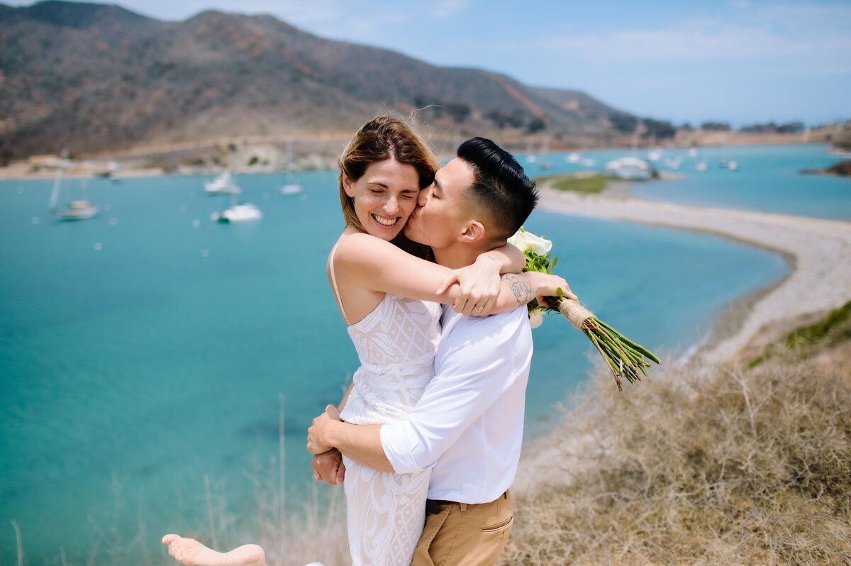 The groom kisses the bride on the check on Catalina Island