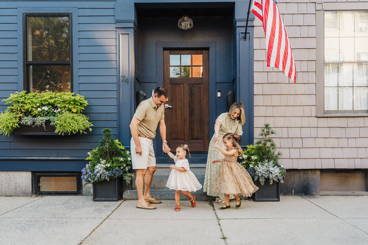 family twirls their daughters in front of blue antique home in boston