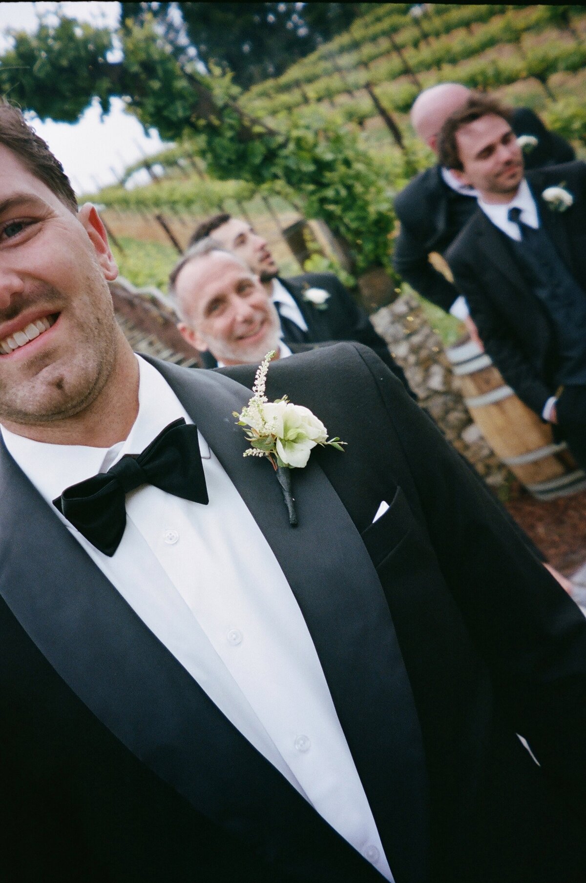 black tux, bow tie, white tea roses, green accents