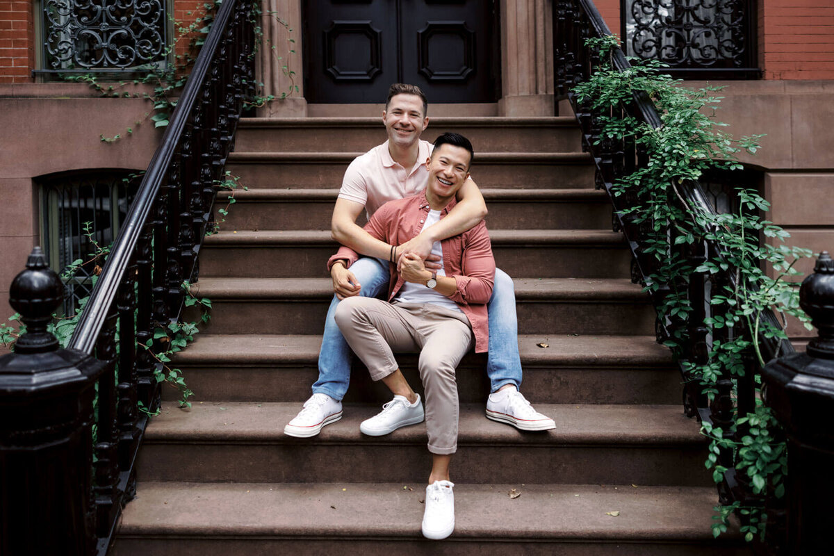 The engaged couple is happily sitting on a staircase of an ivy-covered building at West Village, NYC. Image by Jenny Fu Studio