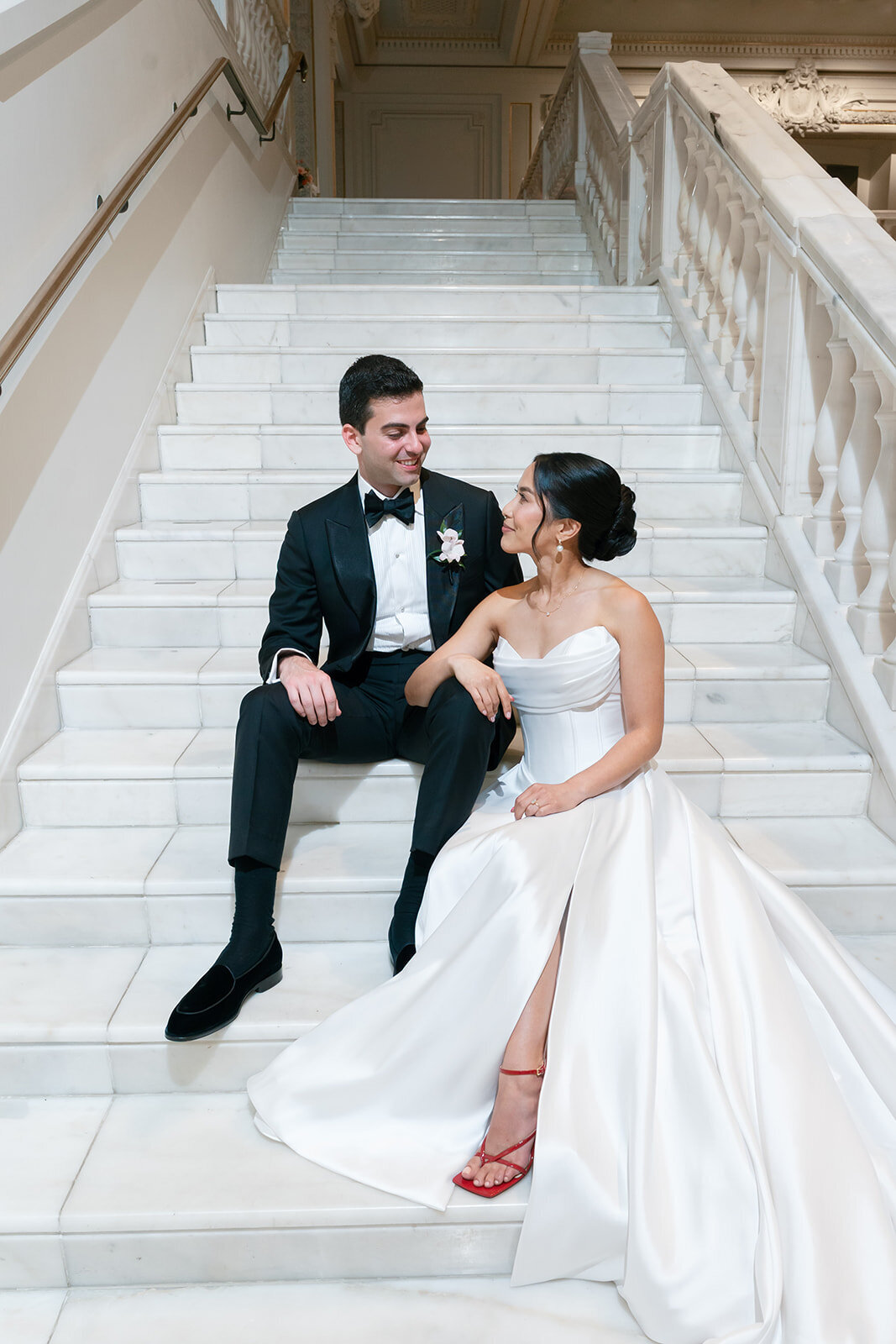 Couple sitting on stairs at venue taking wedding photos. 