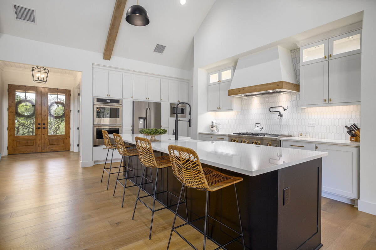 seating at kitchen island with black and white cabinets, white countertops and white backsplash