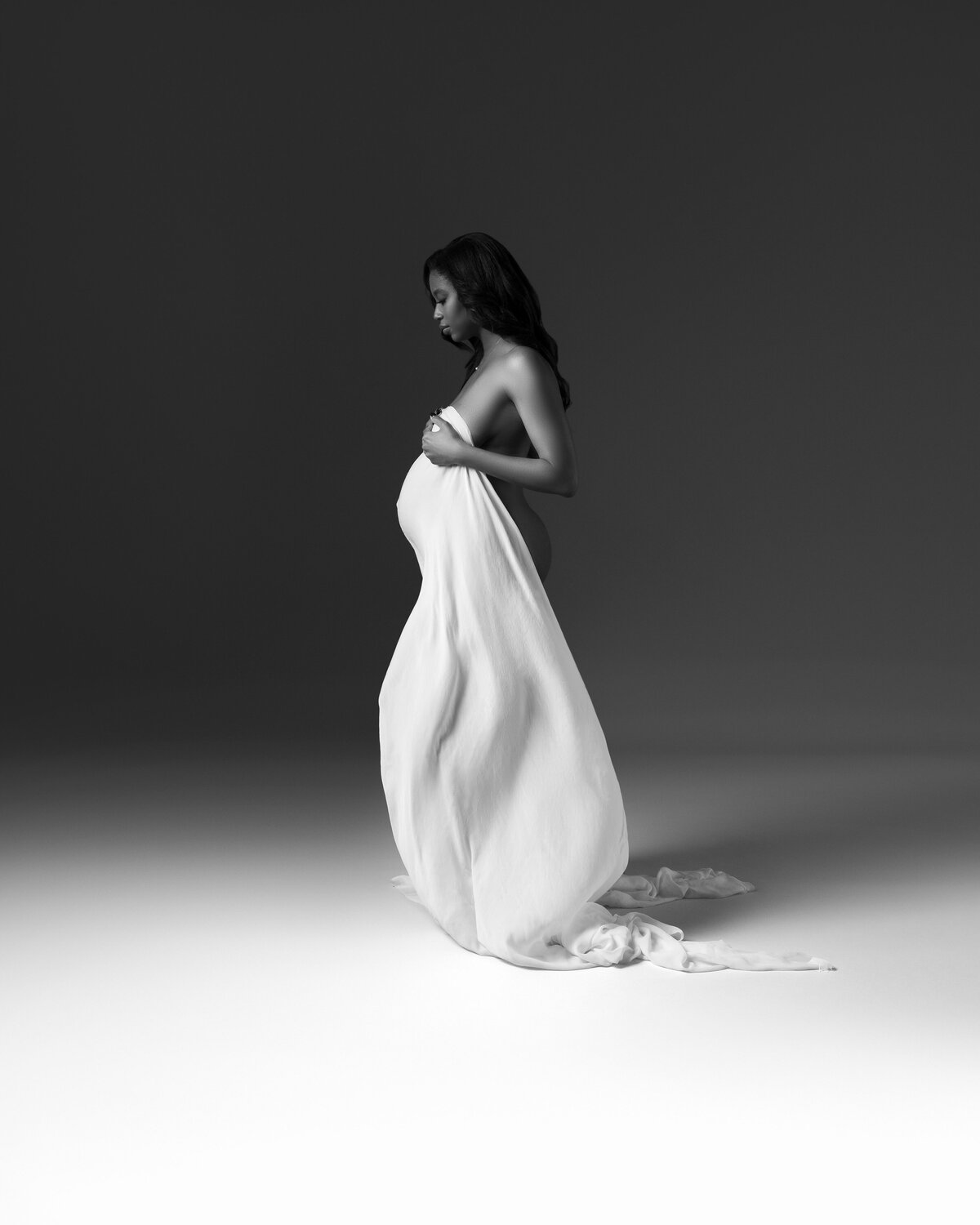 Maternity photo of a black woman with white draping.