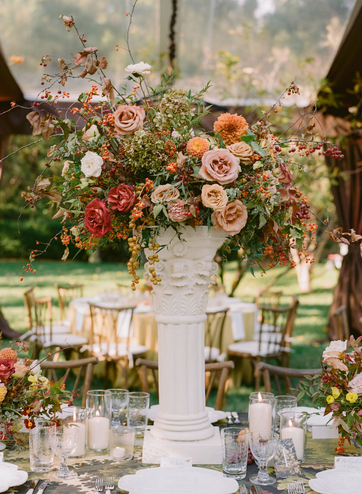 Lush fall florals for low and high centerpieces at fall wedding reception. Clear tented wedding reception in the family's back yard creating an intimate wedding reception environment. Whimsical and organic floral design in colors of copper, yellow, blush,and brown. Fall florals with sweet peas, dahlias, butterfly ranunculus, roses, mums, and bittersweet berries. Design by Rosemary & Finch Floral Design in Nashville, TN.
