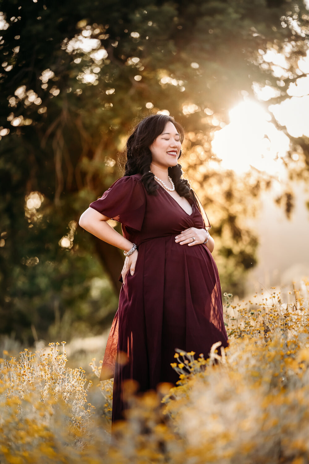 mom in burgundy maternity dress in a lafayette field of flowers.