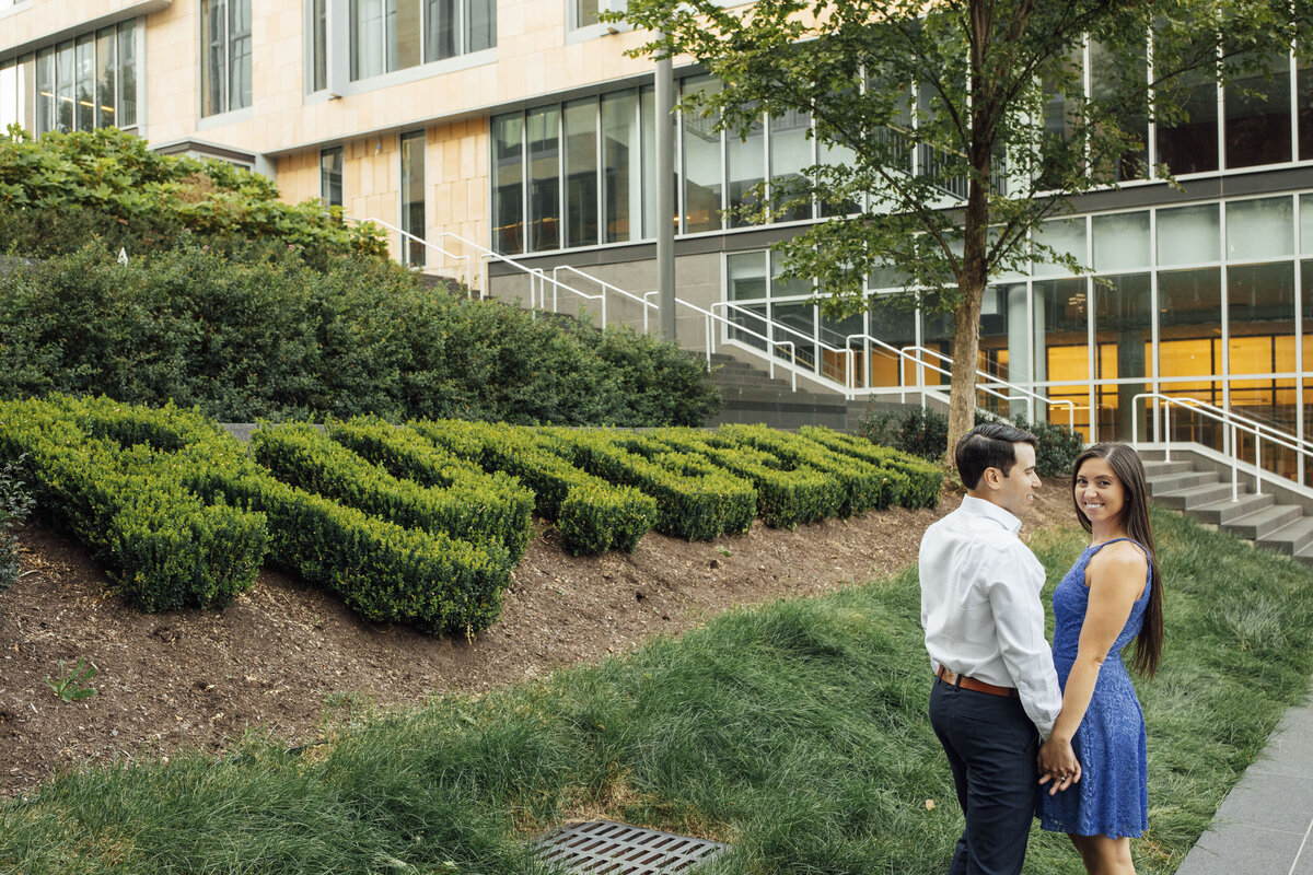 Couple during engagement session by Rutgers Bush sign in New Brunswick New Jersey