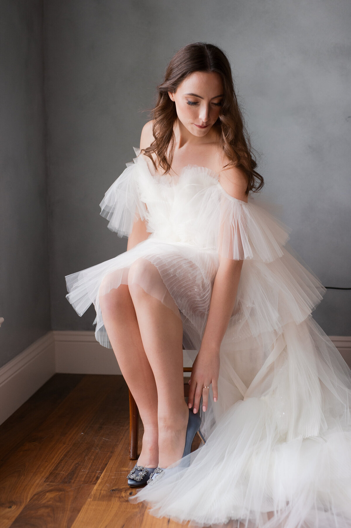 luxury bride in claire la faye gown putting on her manolo blahnik bridal shoes at chateau de lis