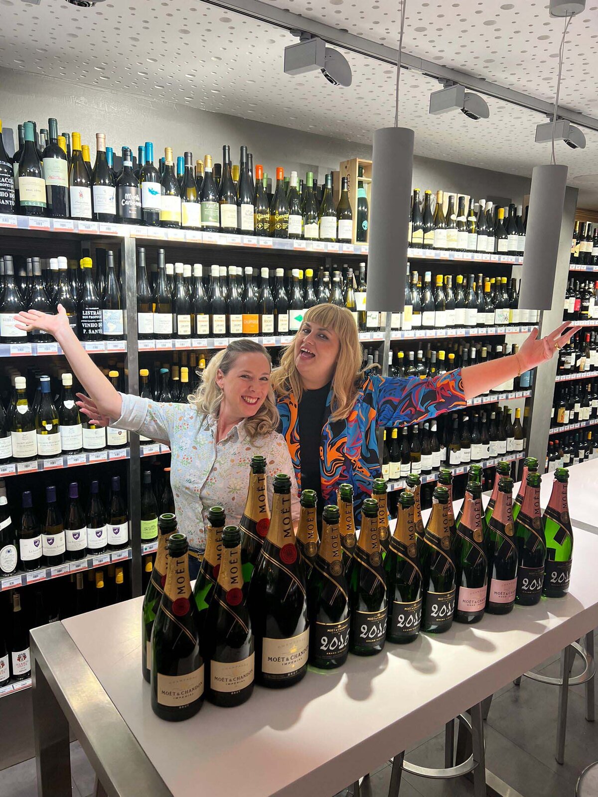 Maria Cristina and a woman standing behind a table full of wine bottles and smiling at Coalla wine bar in Madrid.
