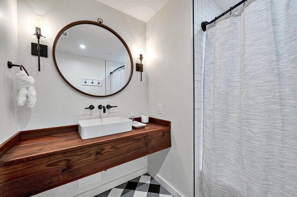 Bathroom with beautiful wood vanity in this four-bedroom, three-bathroom cabin with private garage, firepit, grill, and wi-fi just outside of Waco, TX