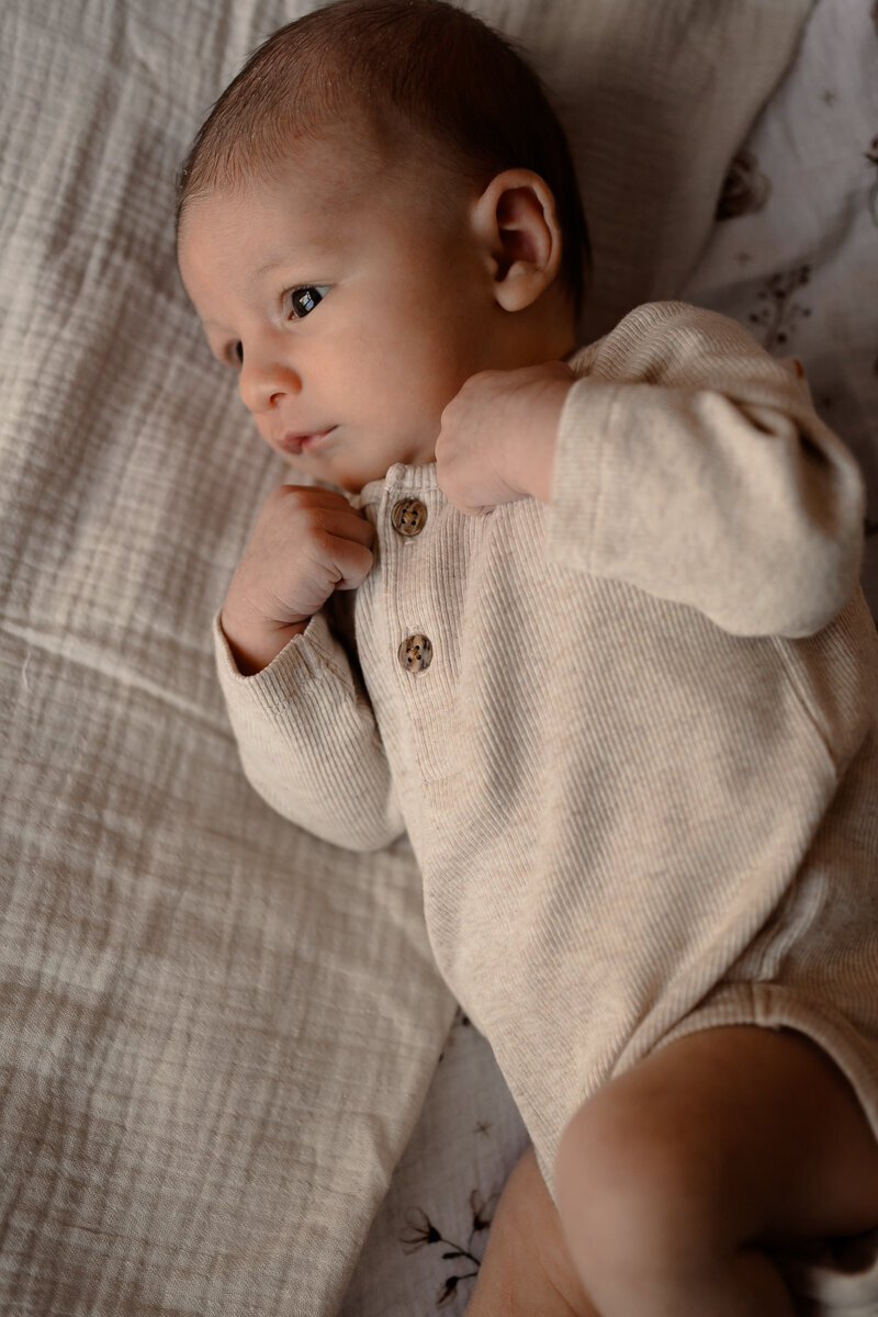 Close up van pasgeboren baby die op zijn zij ligt tijdens een newbornshoot