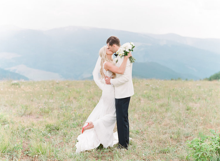 Bride and groom sharing a kiss on top of a mountain in Colorado