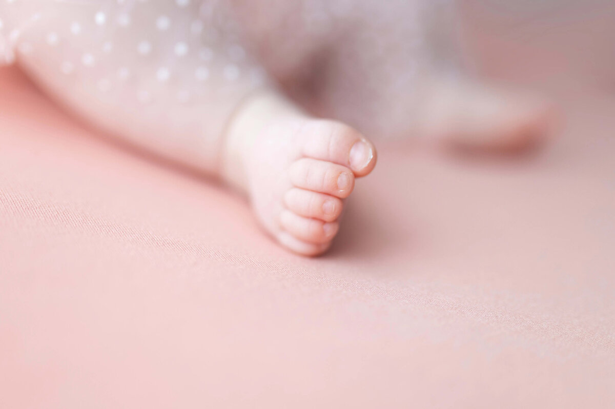Close-up of baby foot on soft pink background - artistic milestone detail photo Maple Grove MN