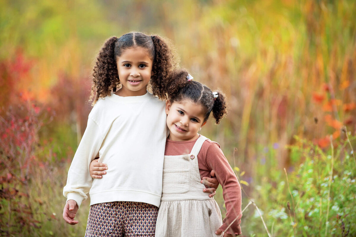 two sisters standing together in a field for their fall family photos in Burlington