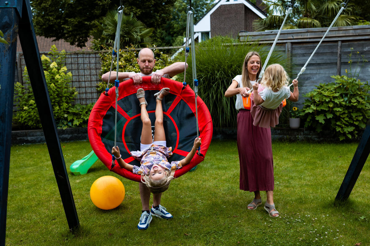 vader moeder en dochters samen schommelen