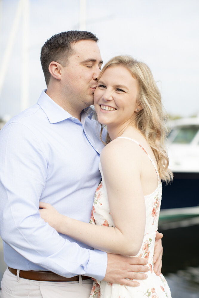 man kisses fiancee's cheek during summer engagement photoshoot