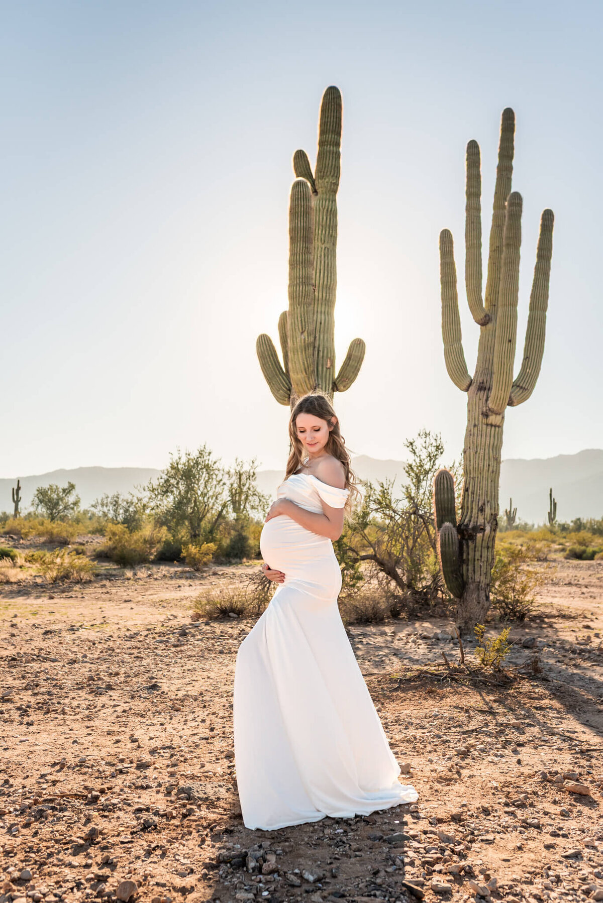 mother-to-be posing in front of two saguaros in Arizona