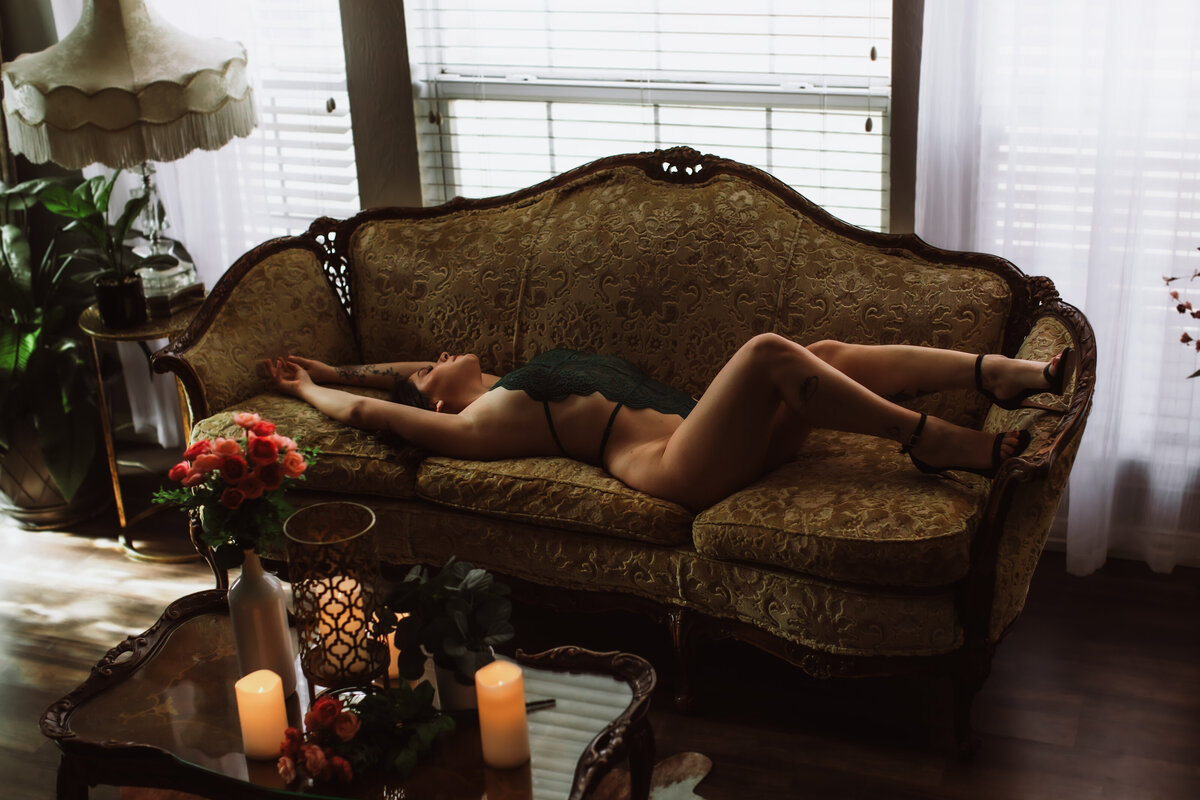 Woman in green lingerie posing confidently on a vintage couch during a boudoir session in Edmond, Oklahoma.
