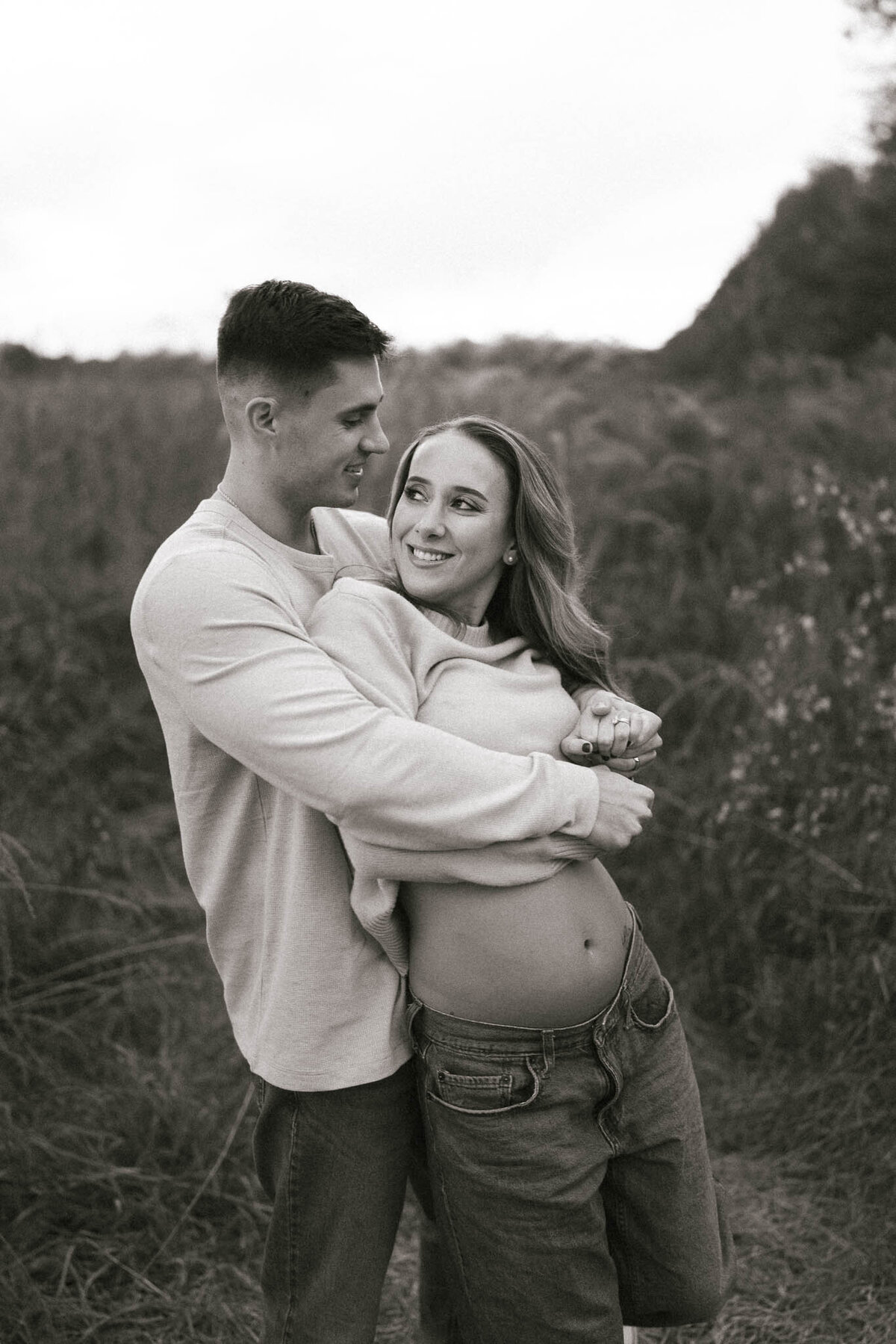 pregnant woman and man hug at seven islands state birding park in october near knoxville tennessee