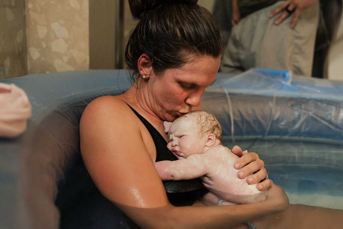 Mother-is-kissing-a-newborn-home-birth-session