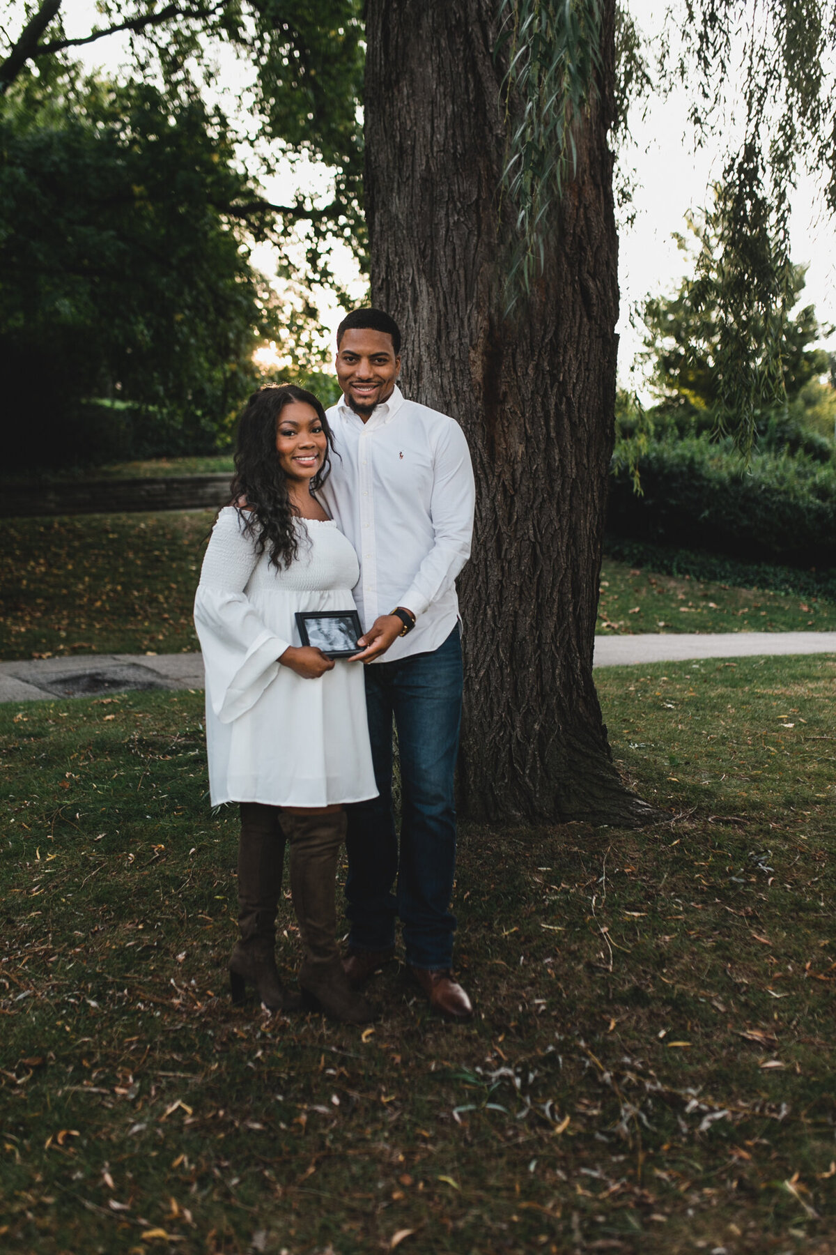 Pregnancy photograph of woman and man holding ultrasound picture.