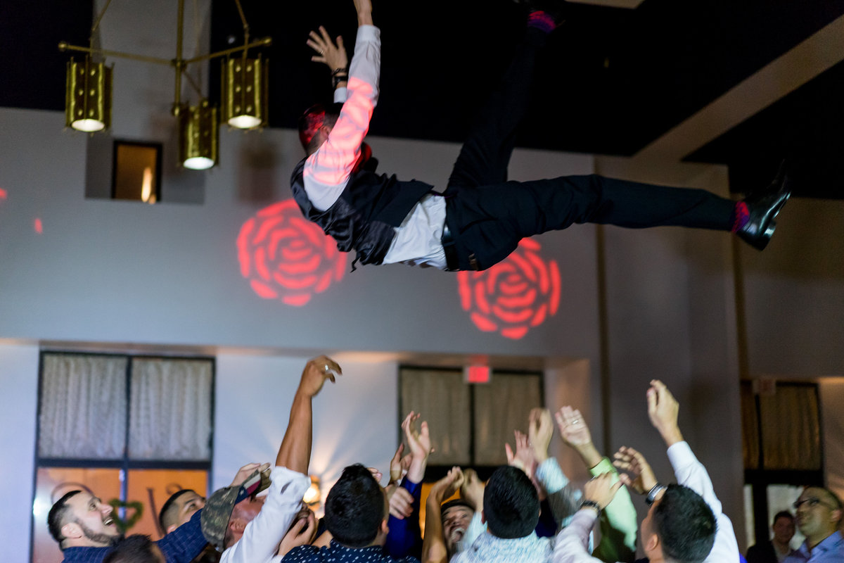 wedding guests toss groom in air during wedding reception at San Fernando Hall in down town San Antonio