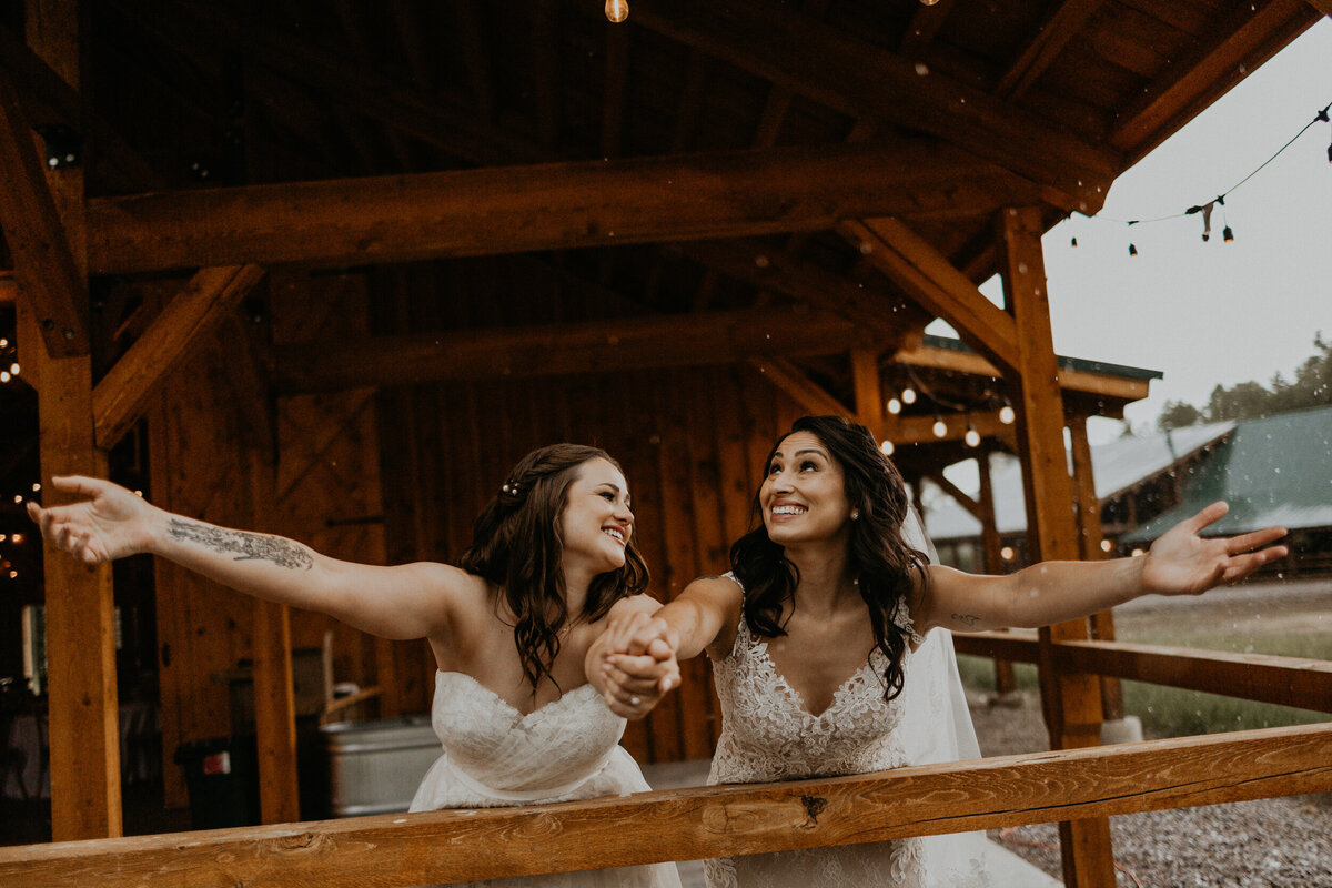 two brides playing in the rain in their wedding dresses